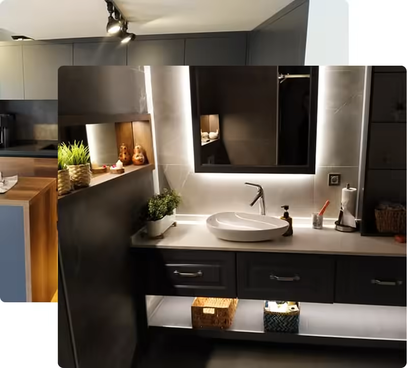 Modern bathroom vanity with round white sink, backlit mirror, and decorative plants on the countertop.